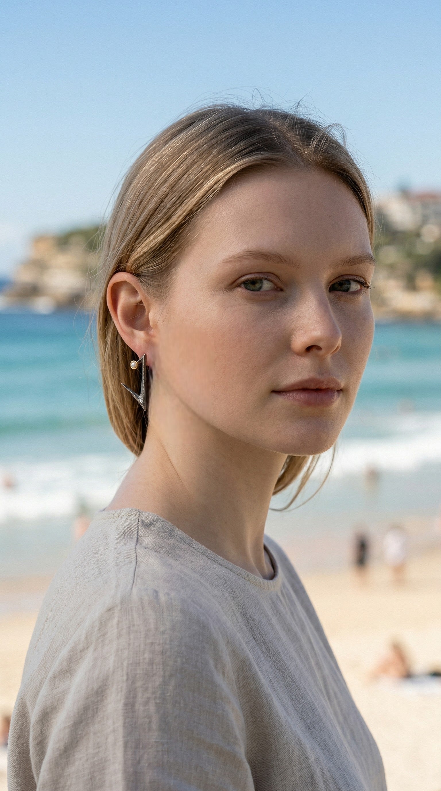 Woman standing on Bondi beach with ocean and sky in the background