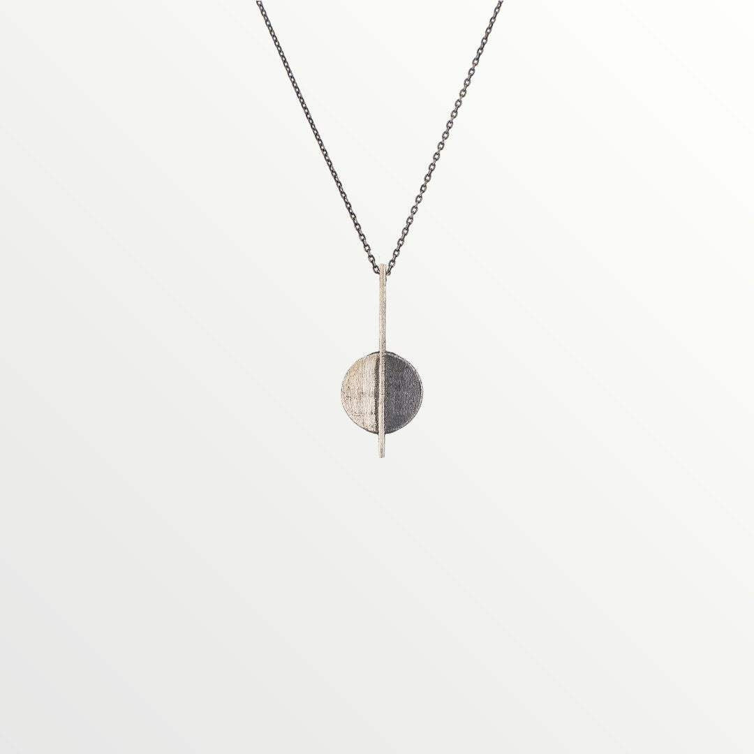 Jouly K handmade silver 925 necklace with oxidized finish, featuring a circular pendant divided into two halves with a vertical bar.