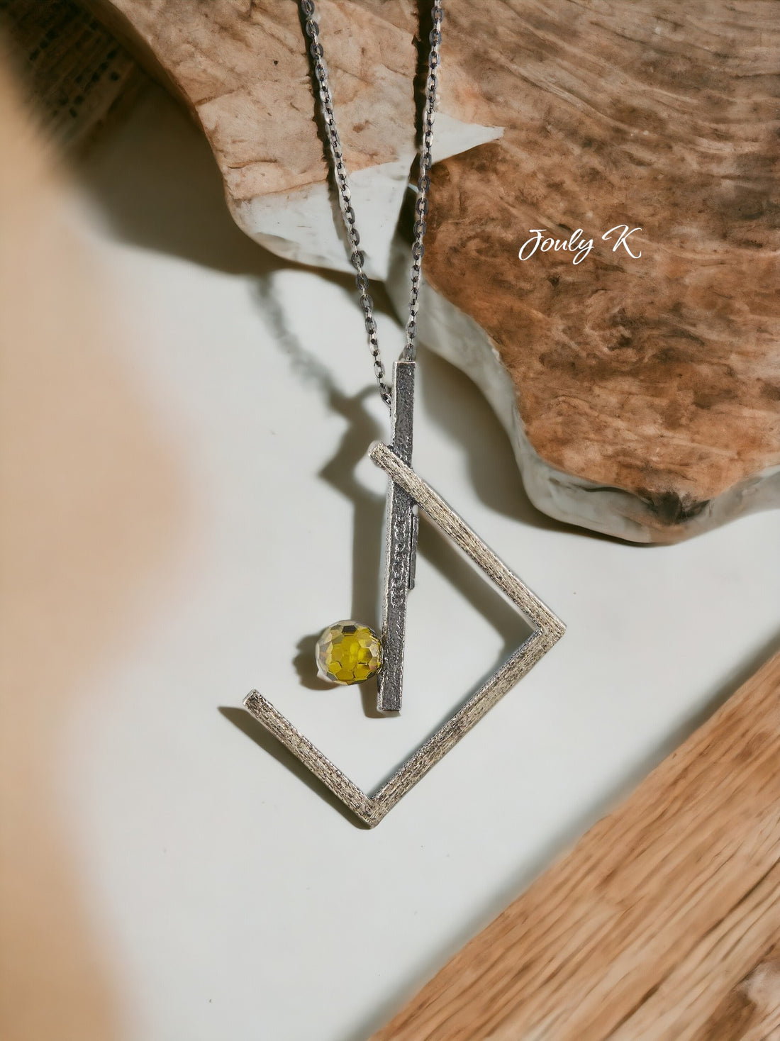 Jouly K handmade silver necklace with oxidized finish and a faceted green glass gem. Features a quirky geometric design.